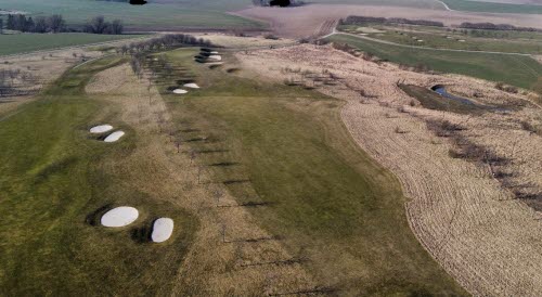 Drönarbild över en grönbrun golfbana tidig vår 2021.