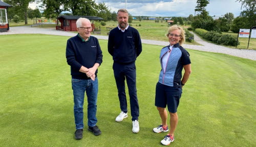 Tre personer, två män och en kvinna, står på en golfbana.