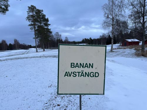 Vy över snötäckt golfbana samt skylten "Banan avstängd."
