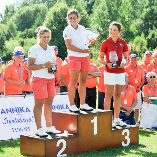 2015 års pristagare i Annika Invitational Europe. Spanska vinnaren Ana Pelaez ler, håller i sin buckla och tittar ner på tvåan som också är spansk. De står på ett podium. På tredje plats står engelska Sophie Lamb och skrattar leende och tittar på tvåan hon med. 