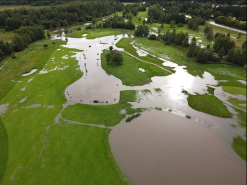 Drönarbild av en översvämmad golfbana. 