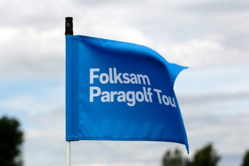 Närbild på blå flagga med texten Folksam Paragolf Tour som vajar i vinden. 