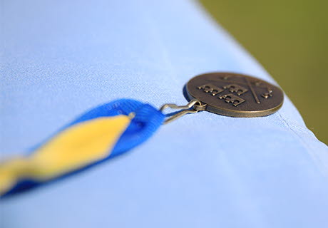 Medalj med SGF:s logotyp och blågult band. Ligger på ett bord med ljusblå duk.